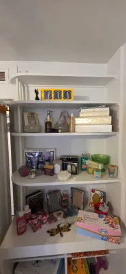Sale Photo Thumbnail #35: Built-in shelving unit filled with various bath products, gift sets, picture frames, and decorative keepsakes.