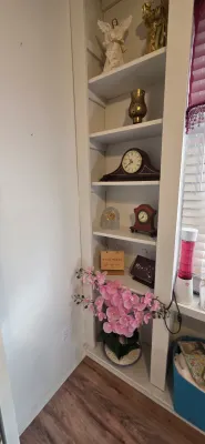 Sale Photo Thumbnail #31: Built-in white shelving unit displaying various home decor items, including mantel clocks, figurines, small signs, and a artificial pink orchid plant.