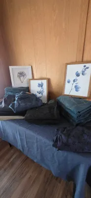 Sale Photo Thumbnail #3: Table display featuring stacks of folded denim jeans alongside framed botanical and geometric prints.