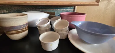 Sale Photo Thumbnail #20: Collection of assorted kitchenware and ceramics, including a studio pottery jar, vintage Corning Ware ramekins with floral accents, a pink mixing bowl, and a periwinkle blue ceramic bowl.
