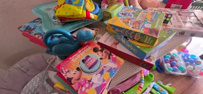 Sale Photo Thumbnail #11: Collection of children's toys and books, including a Minnie Mouse interactive book, board games like Chutes and Ladders, a plastic dinosaur, and colorful play balls.