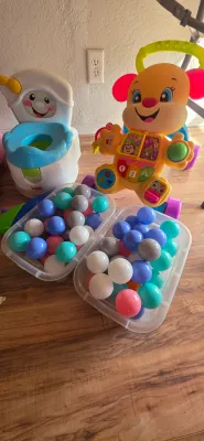 Sale Photo Thumbnail #12: Collection of Fisher-Price toddler items including a puppy walker, training potty, and two plastic bins filled with colorful play pit balls.