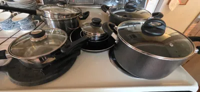 Sale Photo Thumbnail #24: Collection of modern stainless steel and non-stick cookware with glass lids, including saucepans and stockpots.
