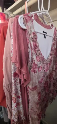 Sale Photo Thumbnail #41: Collection of women's pink and floral tops and dresses hanging in a closet, featuring a velvet rose-patterned tank top with fabric rosette details around the neckline.
