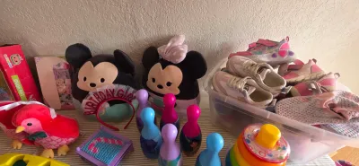 Sale Photo Thumbnail #9: Collection of children's toys and shoes including Mickey and Minnie Mouse Squishmallows, plastic toy bowling pins, a stacking ring tower, plush bird, and various sneakers in a plastic storage tub.