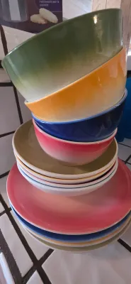 Sale Photo Thumbnail #22: Stack of colorful ombre ceramic dishware, featuring bowls and plates in green, orange, blue, pink, and tan shades.