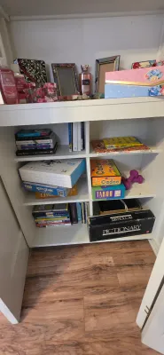 Sale Photo Thumbnail #33: White wooden shelving unit filled with board games including Pictionary and Taboo, books, puzzles, picture frames, and personal care products.
