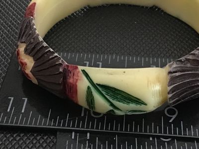 Sale Photo Thumbnail #58: Vintage carved Celluloid bangle bracelet featuring painted floral and fan details in red, green, brown, and cream tones. Measures approximately 3 inches in outer diameter. Shows minor surface wear consistent with age.