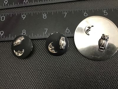 Sale Photo Thumbnail #154: A 3-piece vintage costume jewelry set featuring a circular silver-tone brooch pin and matching clip-on earrings. Each piece features applied raised details of a textured owl and a man-in-the-moon crescent face. The brooch measures approximately 2 inches i
