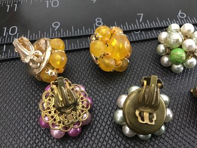 Sale Photo Thumbnail #29: Collection of three pairs of vintage beaded cluster clip-on earrings. Includes one yellow/amber-toned beaded cluster pair, one pink and white faux-pearl cluster pair with filigree detail backing, and one green and faux-pearl cluster pair. Marked 'JAPAN' o