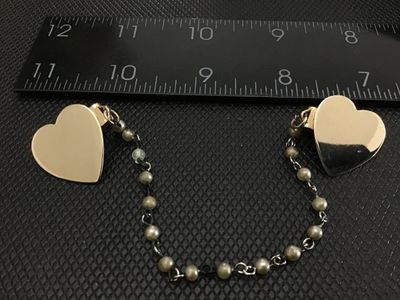 Sale Photo Thumbnail #44: Vintage gold-tone sweater clip / collar guard featuring polished heart-shaped clips connected by a double-linked chain set with faux pearl beads. Measures approximately 4.5 to 5 inches in total length. Clips show light metal wear and tarnish appropriate f