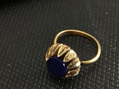 Sale Photo Thumbnail #194: Vintage gold tone cocktail ring featuring a textured crown/petal bezel and a round, flat dark blue cabochon insert. The band appears adjustable. Ring size measures approximately size 7 to 7.5 on a ring mandrel. Good vintage condition with light wear consi