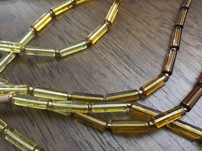 Sale Photo Thumbnail #126: Multi-strand statement necklace featuring earth-toned amber and honey-colored glass bugle beads layered with natural light brown heishe/stone beads. Finished with textured metal end cones and an adjustable hook-and-chain closure. Appears to be in very goo