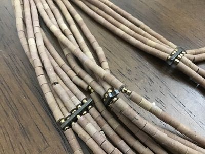 Sale Photo Thumbnail #127: Multi-strand statement necklace featuring earth-toned amber and honey-colored glass bugle beads layered with natural light brown heishe/stone beads. Finished with textured metal end cones and an adjustable hook-and-chain closure. Appears to be in very goo