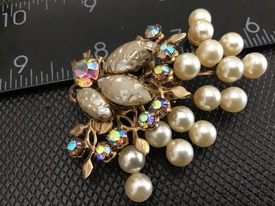 Sale Photo Thumbnail #19: Vintage gold-tone brooch pin featuring faux pearl clusters, textured molded cabochons, and shimmering aurora borealis (AB) rhinestones in a stylized floral spray design. Standard rollover safety clasp on the back. Measures approximately 2.5 inches wide. G