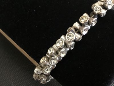 Sale Photo Thumbnail #234: A vintage silver-tone stretch bracelet featuring bezel-set clear rhinestones in flared, hourglass-shaped metal links. Measures approximately 5 inches unstretched. Shows light vintage wear and tarnish to the silver-tone finish; all stones appear present.