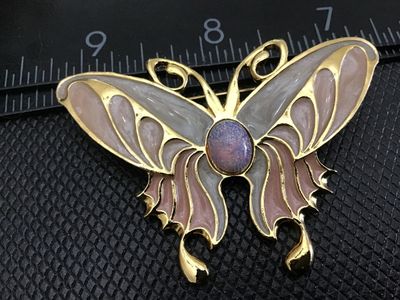 Sale Photo Thumbnail #34: Gold-tone butterfly brooch featuring multi-color pearlescent enamel wings in shades of pink and grey, accented with a purple/iridescent faux opal cabochon center. Pin back clasp is intact and functions properly. Measures approximately 2.5 inches wide. Goo