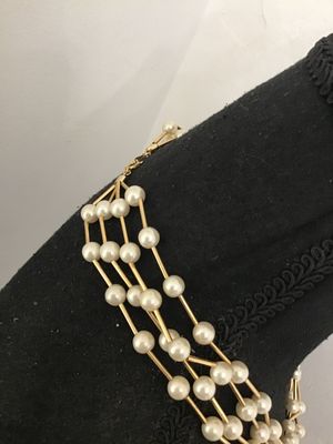 Sale Photo Thumbnail #106: A multi-strand vintage costume necklace featuring cream-colored faux pearls interspersed with gold-tone rigid bar links, creating a dramatic structured lattice or cage effect. Secured with a spring-ring clasp. Shown on a jewelry display bust and alongside