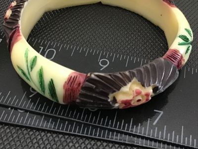 Sale Photo Thumbnail #59: Vintage carved Celluloid bangle bracelet featuring painted floral and fan details in red, green, brown, and cream tones. Measures approximately 3 inches in outer diameter. Shows minor surface wear consistent with age.