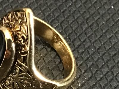 Sale Photo Thumbnail #227: Vintage statement ring featuring an oval black onyx-style cabochon set in an ornate gold-tone filigree frame. The band is stamped "18KT H.G.P." (18K Heavy Gold Electroplate). 

- Ring Size: Approximately size 5 (as measured on mandrel)
- Era/Style: Vintag