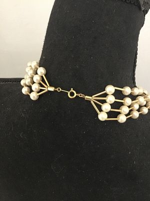 Sale Photo Thumbnail #107: A multi-strand vintage costume necklace featuring cream-colored faux pearls interspersed with gold-tone rigid bar links, creating a dramatic structured lattice or cage effect. Secured with a spring-ring clasp. Shown on a jewelry display bust and alongside