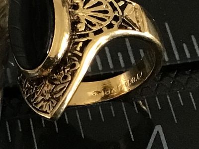 Sale Photo Thumbnail #228: Vintage statement ring featuring an oval black onyx-style cabochon set in an ornate gold-tone filigree frame. The band is stamped "18KT H.G.P." (18K Heavy Gold Electroplate). 

- Ring Size: Approximately size 5 (as measured on mandrel)
- Era/Style: Vintag
