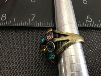 Sale Photo Thumbnail #188: A statement dome-style cocktail ring featuring encrusted, colorful round-cut rhinestones in shades of purple, blue, teal, yellow, and pink. The ring has an antiqued brass-tone finish with a split-shank band. Measures approximately size 6 to 6.5 on a ring 