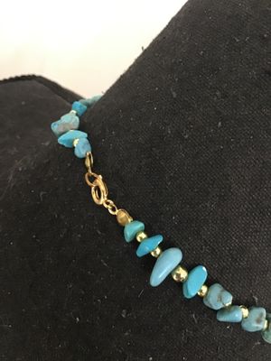 Sale Photo Thumbnail #110: Beaded strand necklace featuring assorted turquoise-colored stone beads, chips, and a central focal bead, interspersed with small gold-tone spacer beads. Finished with a gold-tone lobster claw clasp. Good pre-owned condition with no visible damage.