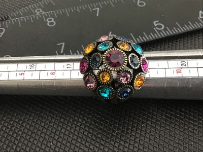 Sale Photo Thumbnail #187: A statement dome-style cocktail ring featuring encrusted, colorful round-cut rhinestones in shades of purple, blue, teal, yellow, and pink. The ring has an antiqued brass-tone finish with a split-shank band. Measures approximately size 6 to 6.5 on a ring 