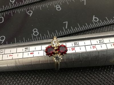 Sale Photo Thumbnail #212: Vintage gold-tone fashion ring featuring four prong-set stones arranged in a cluster: two faceted red/ruby-colored rhinestones and two clear rhinestones. Shows light surface wear and slight tarnish on the metal band consistent with age. Measures approxima