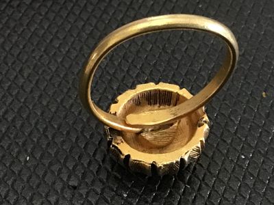 Sale Photo Thumbnail #193: Vintage gold tone cocktail ring featuring a textured crown/petal bezel and a round, flat dark blue cabochon insert. The band appears adjustable. Ring size measures approximately size 7 to 7.5 on a ring mandrel. Good vintage condition with light wear consi