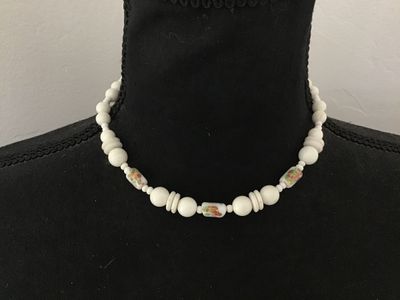 Sale Photo Thumbnail #112: Vintage white beaded choker-style necklace featuring round and disc-shaped white beads interspersed with cylinder glass beads displaying a colorful floral print design. Secures with a traditional gold-tone spring ring clasp. Shows light vintage wear consi