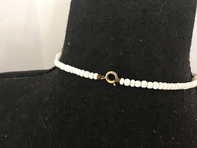 Sale Photo Thumbnail #113: Vintage white beaded choker-style necklace featuring round and disc-shaped white beads interspersed with cylinder glass beads displaying a colorful floral print design. Secures with a traditional gold-tone spring ring clasp. Shows light vintage wear consi