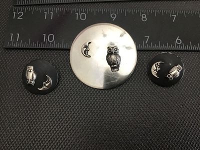 Sale Photo Thumbnail #152: A 3-piece vintage costume jewelry set featuring a circular silver-tone brooch pin and matching clip-on earrings. Each piece features applied raised details of a textured owl and a man-in-the-moon crescent face. The brooch measures approximately 2 inches i