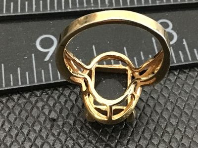 Sale Photo Thumbnail #17: Gold-tone fashion ring featuring a large, emerald-cut black onyx-style stone set in a openwork framework setting with decorative split shoulders. Shown on a ring mandrel measuring approximately size 7.5. Shows minor surface wear and finish rubbing consist
