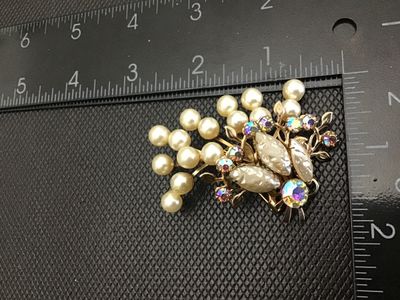 Sale Photo Thumbnail #21: Vintage gold-tone brooch pin featuring faux pearl clusters, textured molded cabochons, and shimmering aurora borealis (AB) rhinestones in a stylized floral spray design. Standard rollover safety clasp on the back. Measures approximately 2.5 inches wide. G