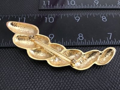 Sale Photo Thumbnail #237: A vintage gold-tone costume jewelry brooch featuring a stylized ribbed or twisted swirl design with a polished finish and textured back. Fitted with a standard pin stem and rollover safety clasp. Measures approximately 3 inches in length. In good vintage 