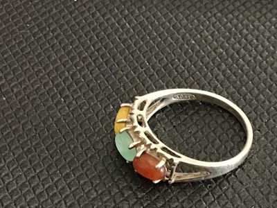 Sale Photo Thumbnail #200: Sterling silver band featuring three oval cabochons in yellow, green, and orange/red tones, possibly multi-colored jade or chalcedony. Inner band is stamped with a maker mark and sterling/925 purity mark. Measures approximately size 7.5 on a ring sizer. S