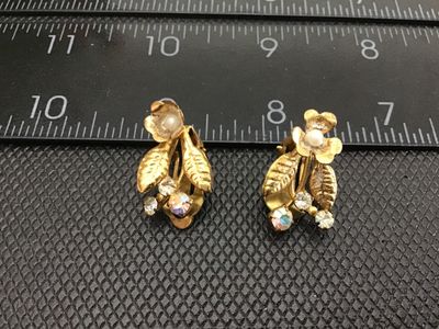 Sale Photo Thumbnail #86: Pair of vintage gold-tone floral clip-on earrings featuring leaves, faux pearl flower centers, and rhinestone accents, including aurora borealis stones. Marked AUSTRIA on the clips. Measure approximately 1 inch in length. Exhibits light vintage wear and p