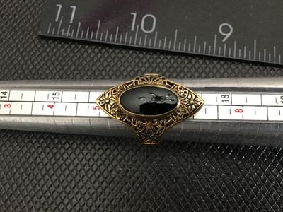 Sale Photo Thumbnail #225: Vintage statement ring featuring an oval black onyx-style cabochon set in an ornate gold-tone filigree frame. The band is stamped "18KT H.G.P." (18K Heavy Gold Electroplate). 

- Ring Size: Approximately size 5 (as measured on mandrel)
- Era/Style: Vintag