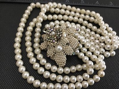 Sale Photo Thumbnail #99: A vintage triple-strand faux pearl necklace featuring an elaborate side clasp decorated with beaded seed pearls and aurora borealis rhinestones in a floral motif. Marked "JAPAN" on the back of the metal setting. Shows light age-appropriate wear, including