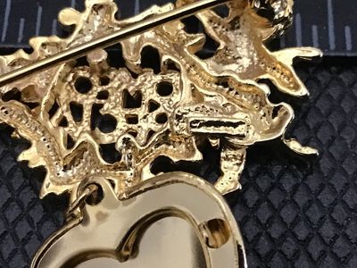 Sale Photo Thumbnail #133: Vintage gold-tone brooch pin featuring a cherub/angel motif with the words 'SOMEONE SPECIAL' in detailed scrollwork, holding a dangling opening heart locket with an engraved double-heart design. Measures approximately 2 inches wide. Pin clasp mechanism wo