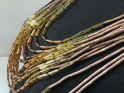 Sale Photo Thumbnail #123: Multi-strand statement necklace featuring earth-toned amber and honey-colored glass bugle beads layered with natural light brown heishe/stone beads. Finished with textured metal end cones and an adjustable hook-and-chain closure. Appears to be in very goo