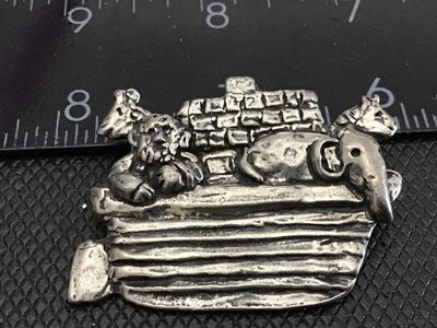 Sale Photo Thumbnail #148: A detailed pewter brooch featuring Noah's Ark with Noah and animals including an elephant and giraffe. Marked 'SHERIDAN' on the back. Measures approximately 1.75 inches wide. Good vintage condition with functional pin closure and aged patina.