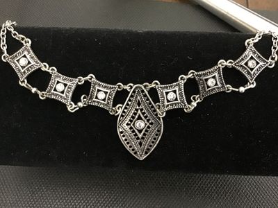 Sale Photo Thumbnail #87: Silver-tone costume jewelry statement necklace featuring openwork geometric/filigree links set with clear rhinestones and a central teardrop-shaped pendant link. Features a lobster claw clasp with an adjustable extender chain. Total chain length is approx