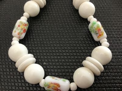 Sale Photo Thumbnail #111: Vintage white beaded choker-style necklace featuring round and disc-shaped white beads interspersed with cylinder glass beads displaying a colorful floral print design. Secures with a traditional gold-tone spring ring clasp. Shows light vintage wear consi