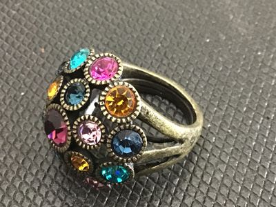 Sale Photo Thumbnail #190: A statement dome-style cocktail ring featuring encrusted, colorful round-cut rhinestones in shades of purple, blue, teal, yellow, and pink. The ring has an antiqued brass-tone finish with a split-shank band. Measures approximately size 6 to 6.5 on a ring 