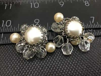 Sale Photo Thumbnail #24: Pair of vintage clip-on cluster earrings featuring central faux pearl cabochons framed by silver-tone filigree metalwork, surrounded by dangling faceted clear crystal beads and smaller accent faux pearls. Measure approximately 1.25 inches across. Shows mi