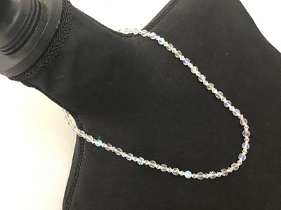 Sale Photo Thumbnail #117: A vintage single-strand necklace featuring faceted clear glass beads with an iridescent Aurora Borealis (AB) coating. The necklace is finished with a filigree push-in box clasp. Appears to be in good vintage condition with no missing beads observed.