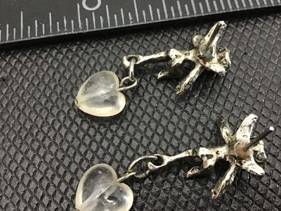 Sale Photo Thumbnail #8: Pair of detailed cherub/angel stud earrings featuring dangling clear glass or quartz heart charms. Measures approximately 1 inch in total length. Silver-tone metal shows light vintage patina, good pre-owned condition with post backs.